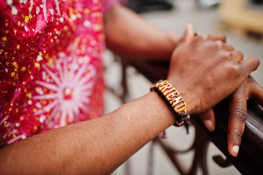 Hand with bracelet friends of a black young man wearing african traditional red colorful clothes. photo