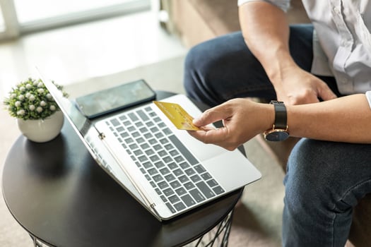 Man holding credit card with laptop and mobile phone sitting on sofa at home, businessman shopping online, e-commerce, internet banking, spending money, working from home concept, photo