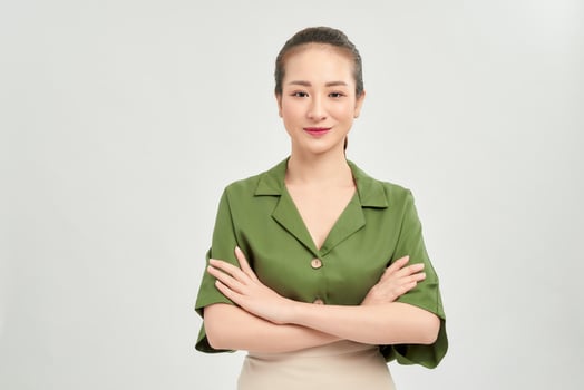 Portrait of a smiling asian businesswoman standing with arms folded and looking at camera isolated over white background photo