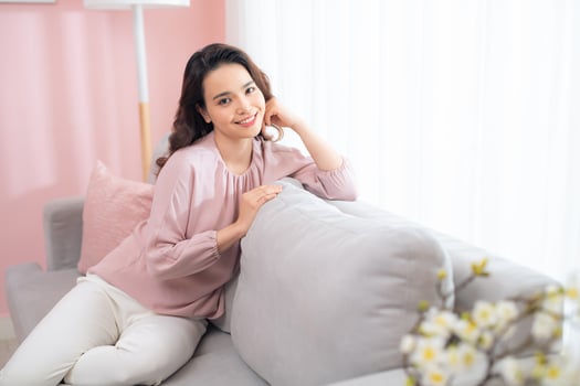Happy young Asian woman sitting on sofa and relaxing at home. photo