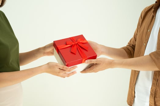 Close-up of man giving red gift box to woman over white background photo