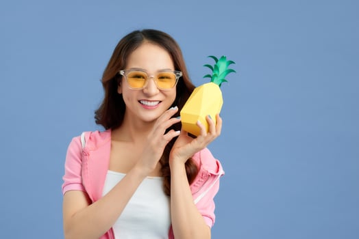 Fashion summer portrait Asian girl in sunglasses and paper pineapple over blue background photo