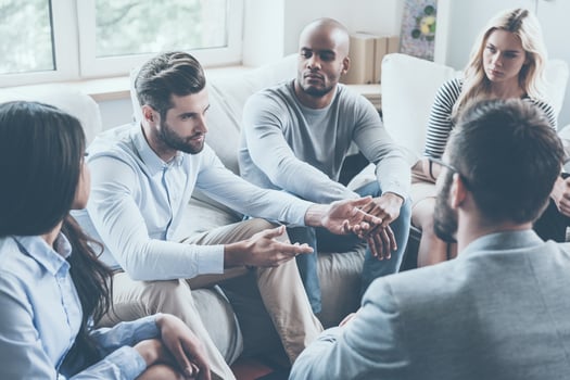 Sharing his problems with group. Group of young people sitting in circle while one man telling something and gesturing photo