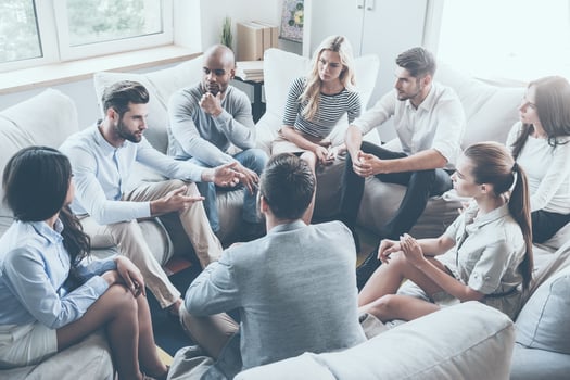 Group therapy. Group of young people sitting in circle while one man telling something and gesturing photo