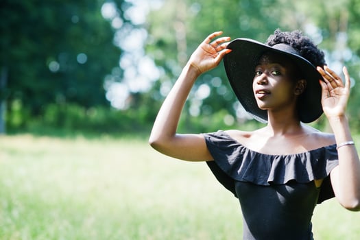 Portrait of gorgeous african american woman 20s in summer hat posing at green grass in park. photo