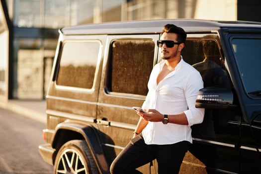 Solid asian man in white shirt and sunglasses posed near black mafia suv car. photo