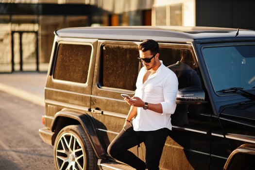 Solid asian man in white shirt and sunglasses posed near black mafia suv car. photo