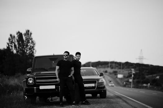 Two asian brothers man wear on all black posed near suv cars. photo