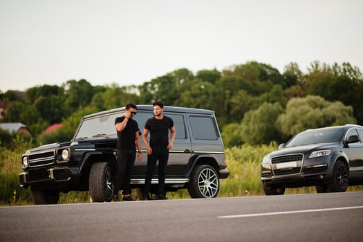 Two asian brothers man wear on all black posed near suv cars. photo