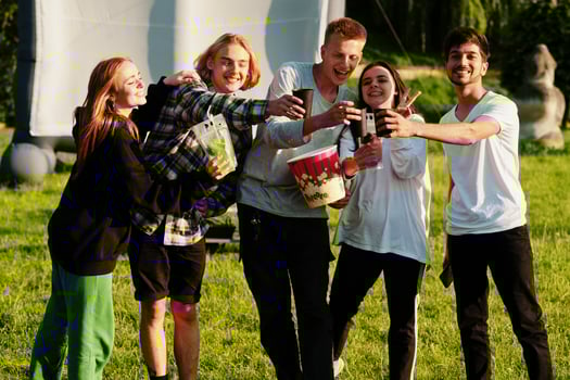 Young multi ethnic group of people watching movie at poof in open air cinema. photo