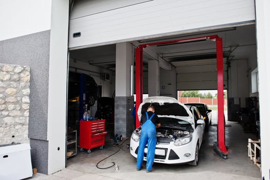Car repair and maintenance theme. Mechanic in uniform working in auto service. photo