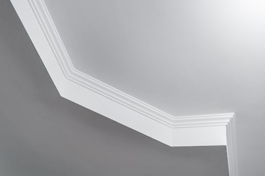 Detail of corner ceiling with intricate crown molding. Suspended ceiling and drywall construction in empty room in apartment or house. Stretch ceiling white and complex shape. photo