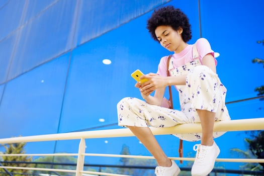 Black woman surfing cellphone on railing photo