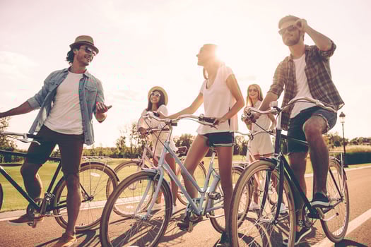 Friends will be friends. Low angle view of cheerful young people talking while standing near their bicycles on the road photo