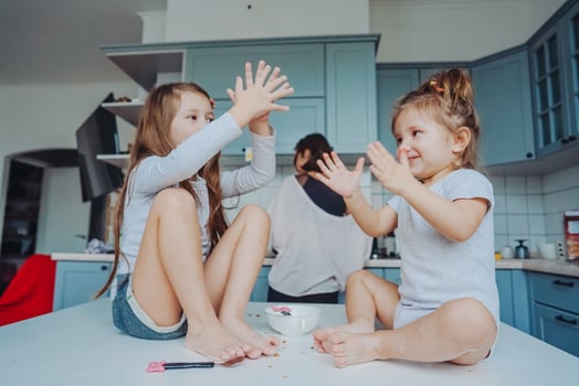 Two little girls in the kitchen sitting on the table. photo