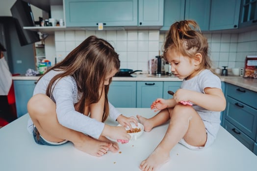 Two little girls in the kitchen sitting on the table. photo