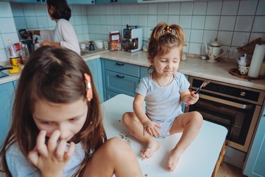 Two little girls in the kitchen sitting on the table. photo