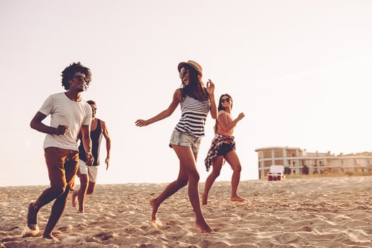 Young and free. Group of young cheerful people running along the beach and looking happy photo