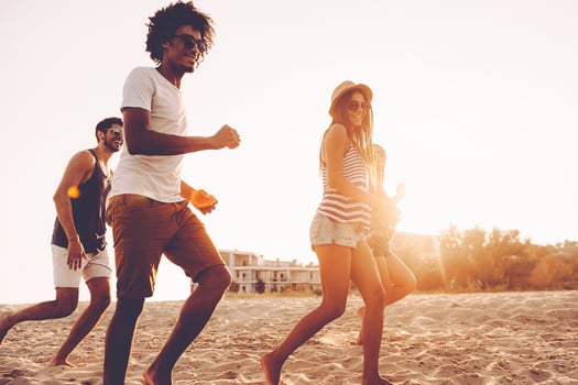Just keep running Group of young cheerful people running along the beach and looking happy photo