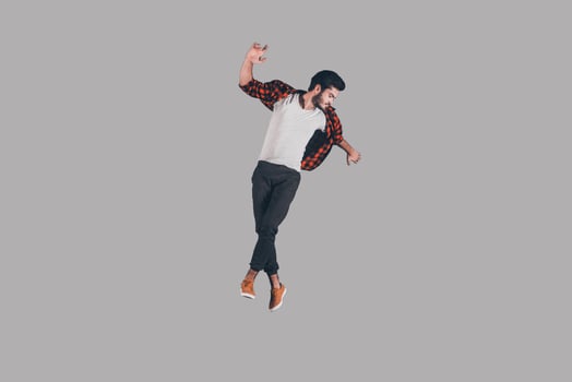 Young and carefree. Mid-air shot of handsome young man jumping and gesturing against background photo