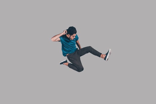 Cool and free. Mid-air shot of handsome young man in cap jumping and gesturing against background photo