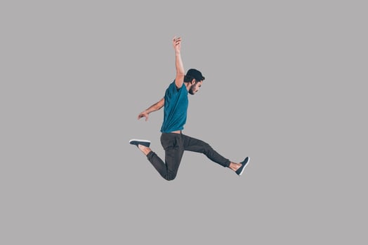 Like a rock star. Mid-air shot of handsome young man in cap jumping and gesturing against background photo