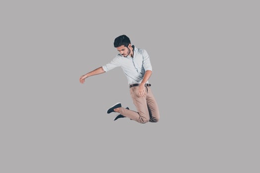 Man in mid-air. Mid-air shot of handsome young man jumping and gesturing against background photo