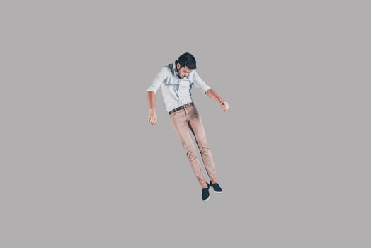 Free falling. Mid-air shot of handsome young man jumping and gesturing against background photo