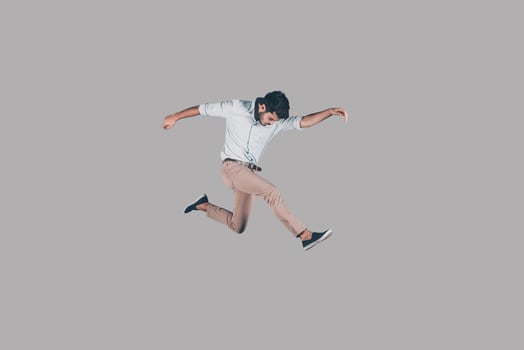 Man jumping. Mid-air shot of handsome young man jumping and gesturing against background photo