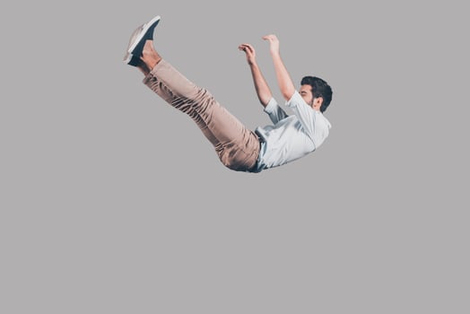 Free falling. Mid-air shot of handsome young man falling against grey background photo