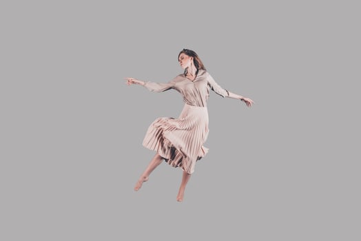 Dancing queen. Studio shot of attractive young woman in beautiful dress hovering in air photo