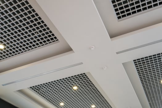 suspended and grid ceiling with halogen spots lamps and drywall construction in empty room in store or house. Stretch ceiling white and complex shape. photo