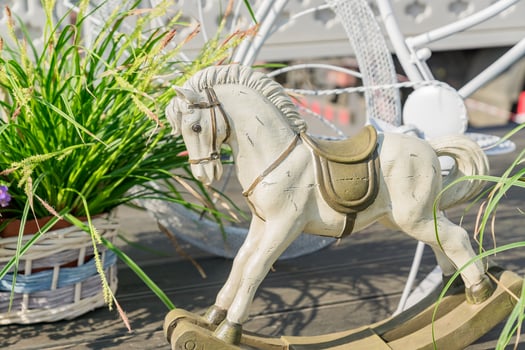 Statue of white clay horse near green plants in whickered pots. Garden decoration arrangement photo