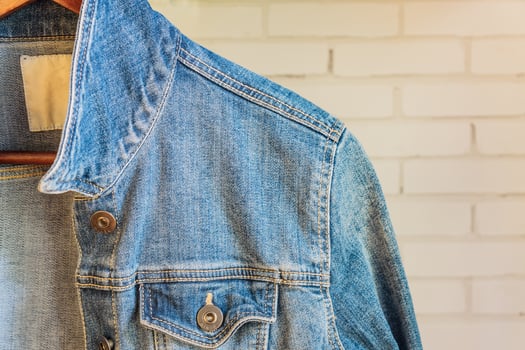 Blue denim woman jacket on a wooden hanger. Trendy clothes. photo