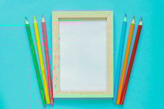 Creative flat lay with school suppllies. Mock up frame and multicolored pencils on blue background. Back to school. photo