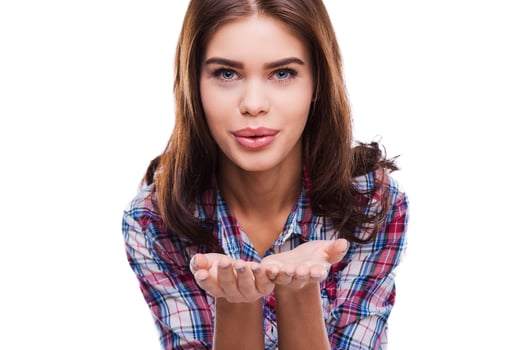 Flirting beauty. Beautiful young woman in shirt sending a kiss at camera while standing against white background photo