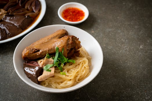 dried noodles with braised duck in white bowl photo