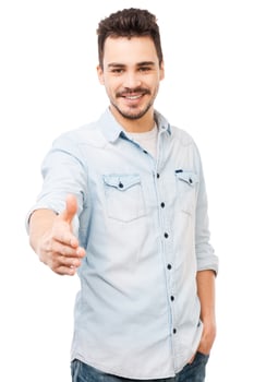 Nice to meet you Portrait of cheerful young man stretching out hand for shaking while standing against white background photo