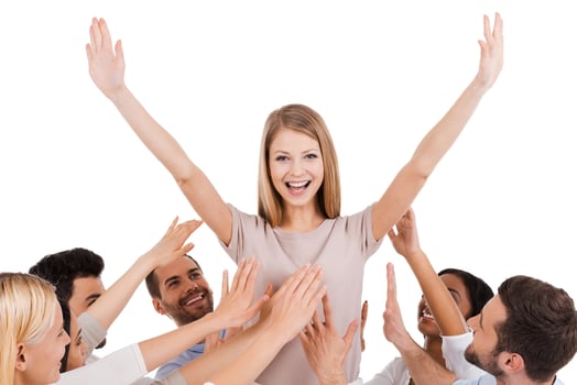 She is a real leader. Happy young woman standing against white background and keeping arms outstretched while group of excited people stretching hands to her and smiling photo