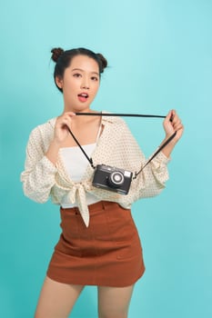 photography and people concept - smiling teenage girl with digital camera over blue background photo