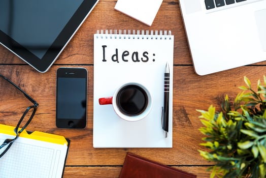 Hot coffee for fresh ideas. Top view of note pad with coffee cup laying on the wooden desk with different business stuff around it photo