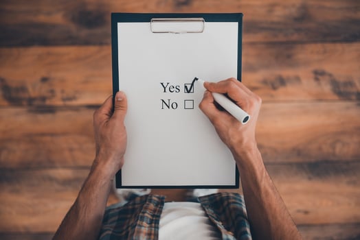 Making a right choice. Top view of man making a check mark in clipboard while standing on the wooden floor photo