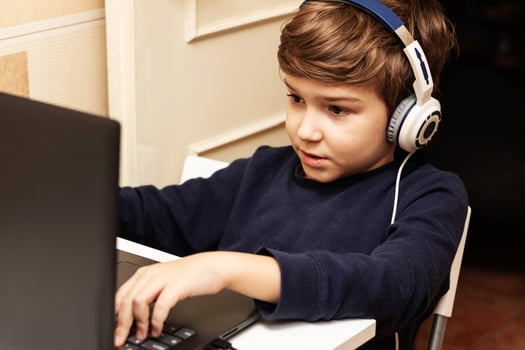 Little boy playing games on laptop while relaxing at home. photo