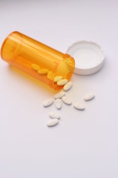 Oval pills and orange pill bottles were spread out on the white tabletop. photo