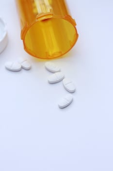 Oval pills and orange pill bottles were spread out on the white tabletop. photo