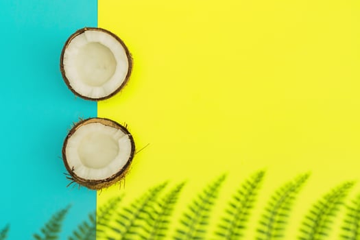 Halves of fresh raw coconut on yellow and blue backgound. Top view, flat lay photo