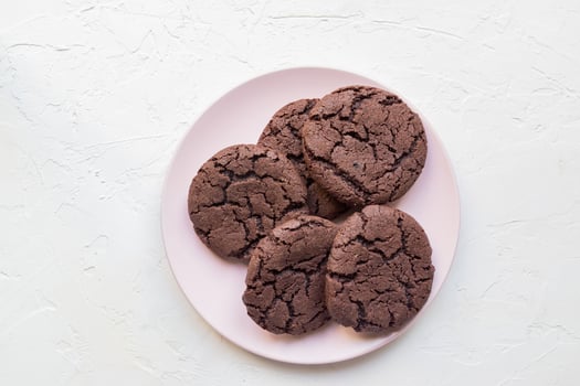Top view of chocolate chip cookies on a pink plate on white concrete background. From above. copy space photo