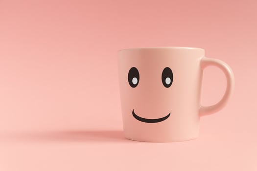 Pink cup on pink background. Smiling face on a mug. Minimal creative concept photo