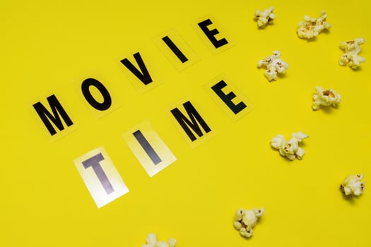 Movie Time text lettering with scattered salty popcorn on yellow background photo