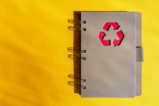 Planner of notebook with recycling sign on a cover on orange background. Consept of waste recycling. Top view, copy space. photo